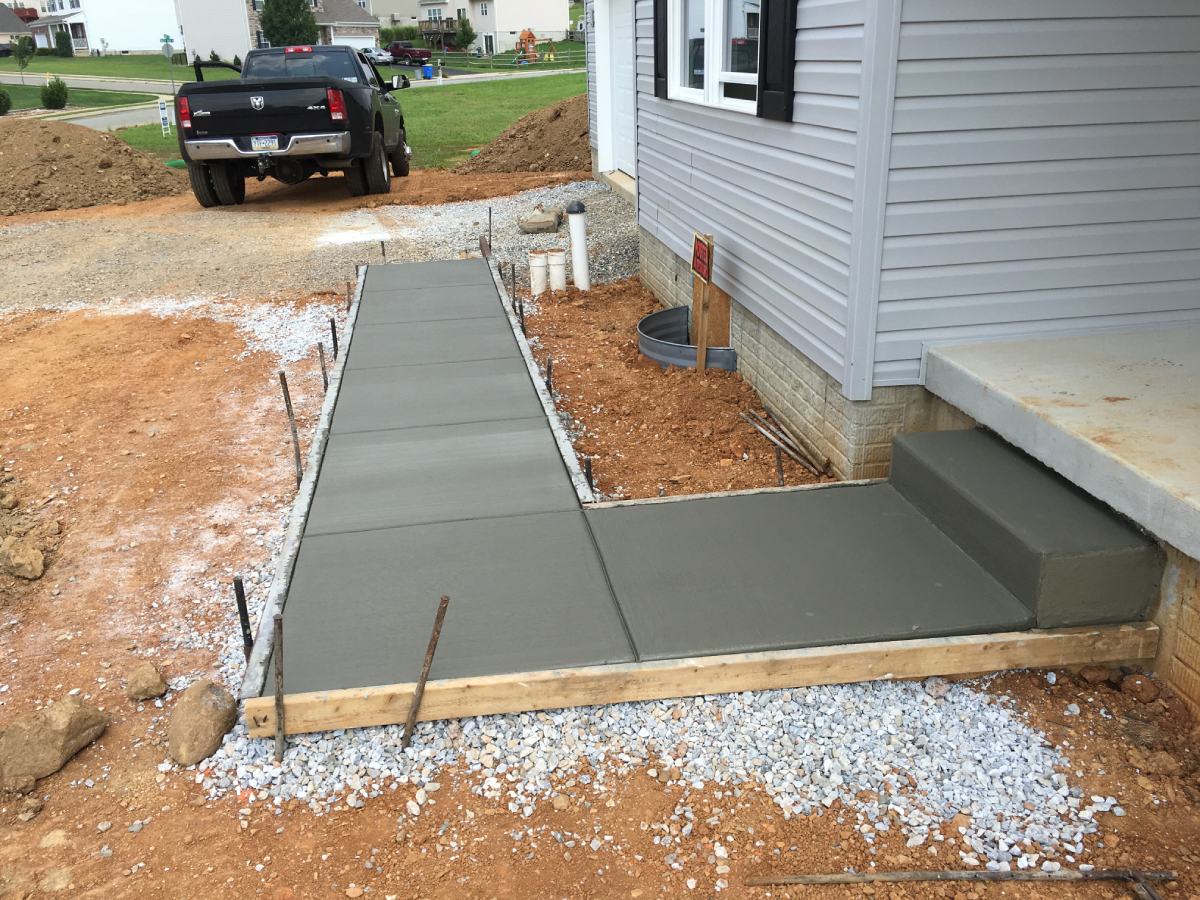 A concrete slab being installed in front of a house.