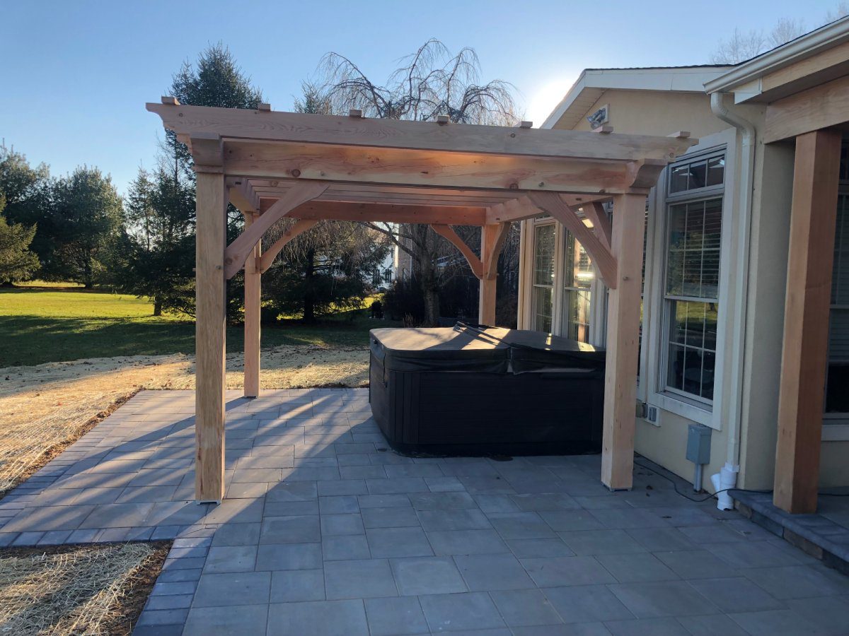 A patio with an outdoor hot tub and pergola.