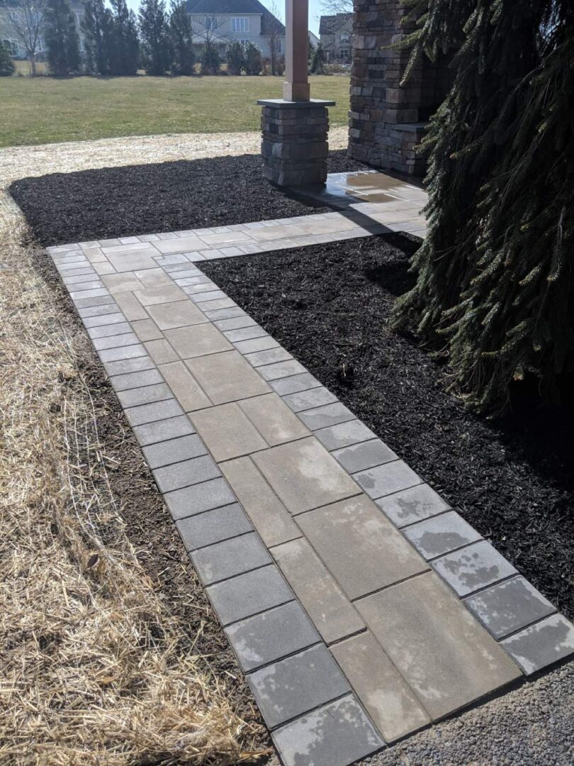 A walkway with a brick pattern and black mulch.