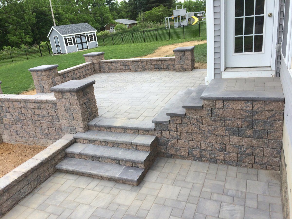 A patio with steps and a wall of bricks.