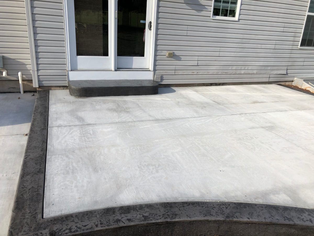 A concrete patio with a door and window.
