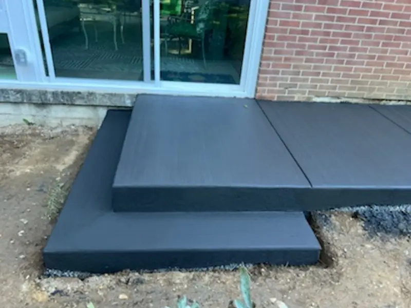 A black concrete slab sitting in the middle of a yard.