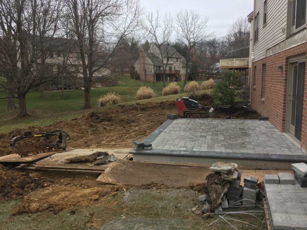 A concrete slab being installed in the middle of a yard.