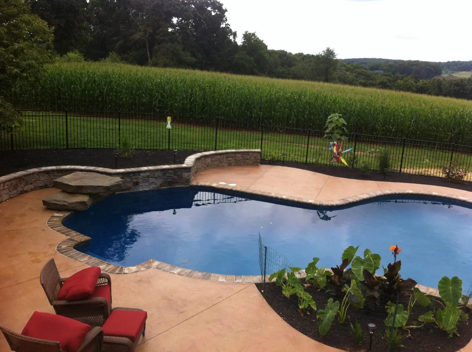 A pool with a brick deck and a stone wall.
